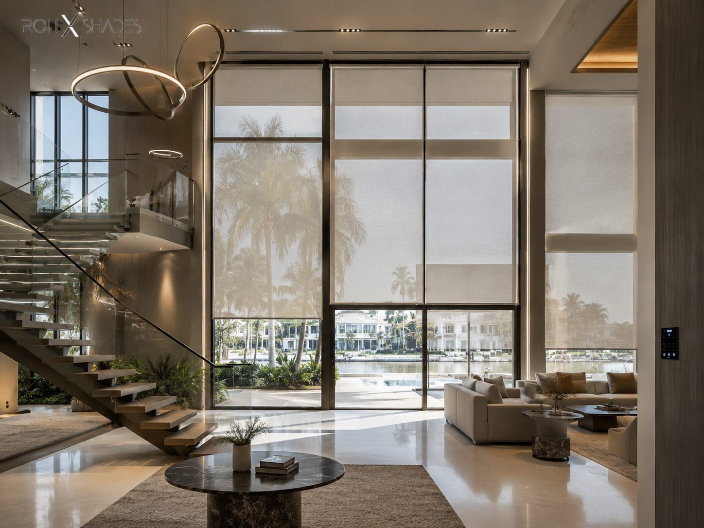 Motorized shades set at different heights across a double-height waterfront residence