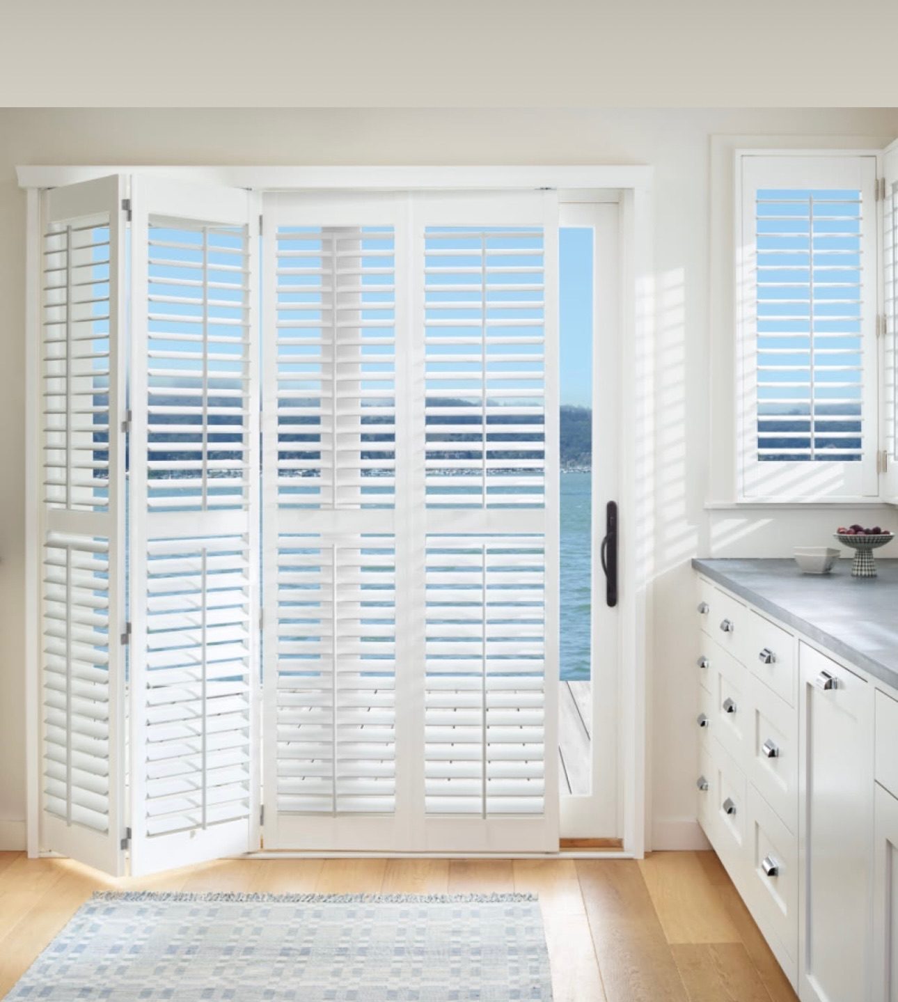 White shutters on a French door and side window, folded back to clear the handle and the traffic path.