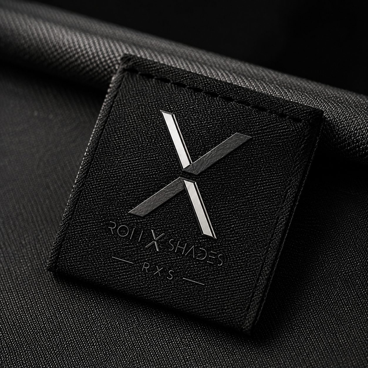 Emblema X de Rollx en plata sobre una etiqueta tejida negra; concepto de materiales de la marca