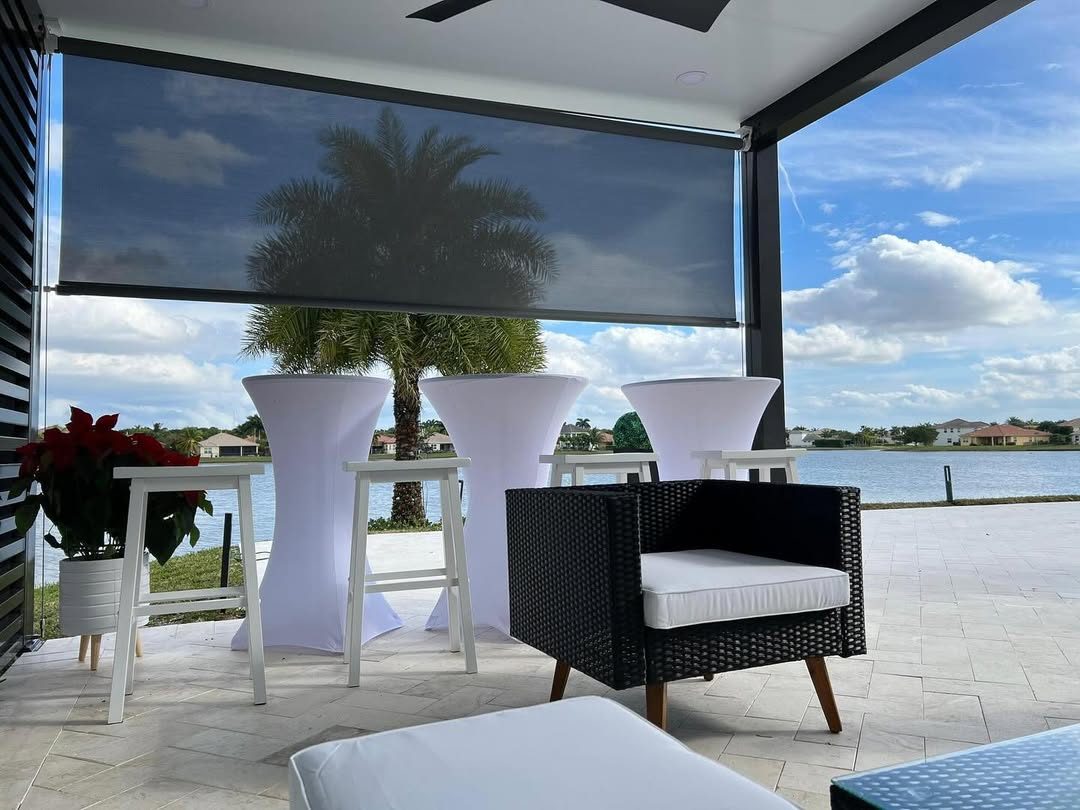 A solar screen part-lowered on a lakefront terrace, cutting the low sun while the water view stays open beneath it.