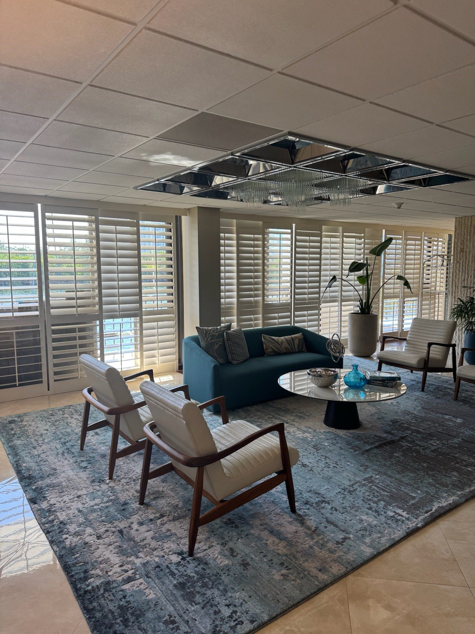 White shutters wall to wall in a waterfront lounge, dividing rails set at seated eye level.